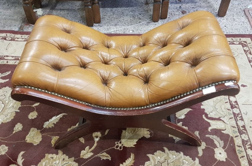 A large Chesterfield deep buttoned leather x framed hardwood stool